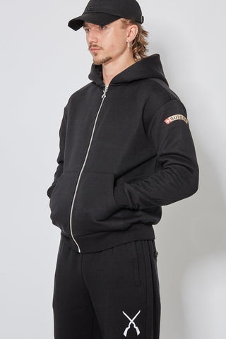 Schwarzer CH+ARMED Infanterie Zip Hoodie, angewinkelte Ansicht mit Stickerei, Badge und Reissverschlussanhänger.