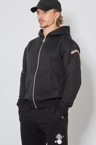 Schwarzer CH+ARMED Isone Gren Zip Hoodie, angewinkelte Ansicht mit Stickerei, Badge und Reissverschlussanhänger.