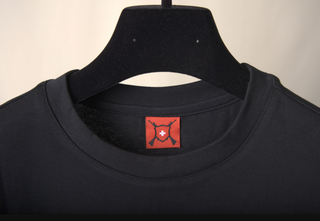 Ein eingenähtes Etikett welches das CH+ARMED Logo abbildet im Nacken eines T-Shirt