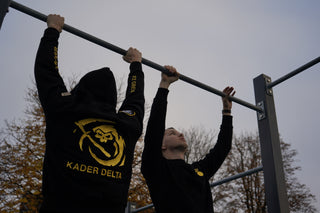 Zwei Personen in Kader Delta Zugskleidung an einer Klimmzugstange