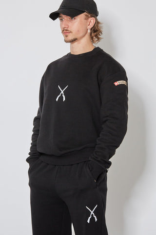 Schwarzes CH+ARMED Sweatshirt für Herren mit weissem Infanterie Logo auf der Brust, lockerer Schnitt, kombiniert mit schwarzer Cap und Jogginghose mit weissem Infanterie Stick – Seitenansicht